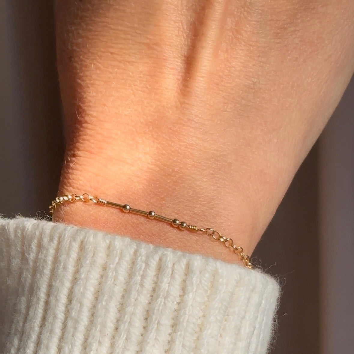 Model wearing gold morse code bead bracelet. delicate bracelets, one gold and one silver, with small beads spaced evenly along the length of each bracelet. Pinky promise. Morse code bead jewelry, morse code beaded jewelry, secret message jewelry, bff jewelry, bff bracelet, pinky promise bracelet, secret message bracelet, hidden message jewelry, hidden message bracelet, sterling silver, gold, adjustable bracelets, delicate bead bracelet, new product, delicate pattern of dots and dashes bracelet