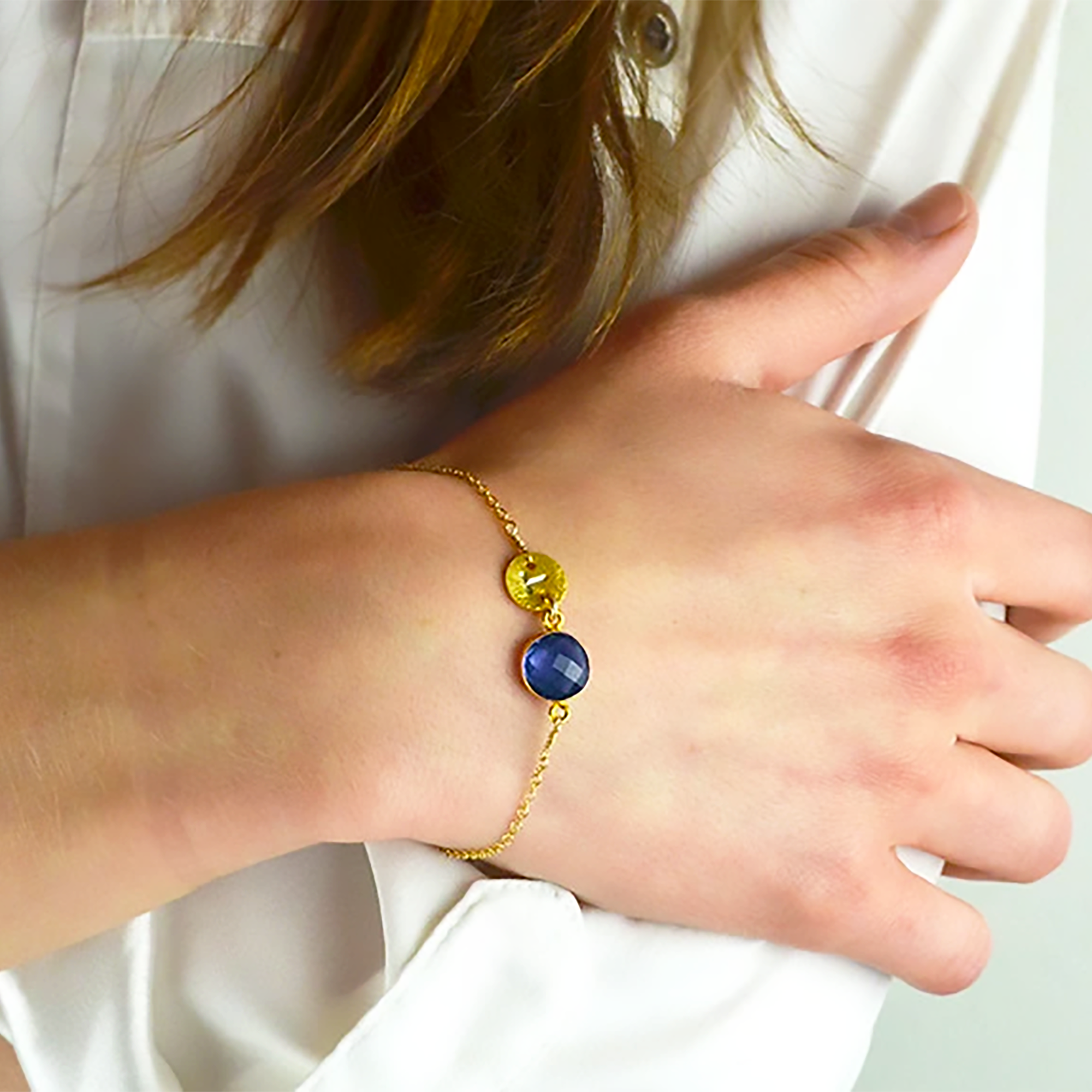 Model in white top is wearing a gold filled brushed disk bracelet with the kyanite quartz birthstone. Hand stamped initial bracelet. Birthstone bracelet. Oval disk. 