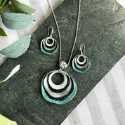 beautiful three-ring circles statement necklace and earrings set with silver and blue tones. Necklace is made with a steel cable chain and a zinc alloy pendant with a galvanic finish. 
