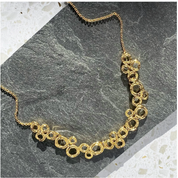 A gold necklace with a chain and a pendant made of multiple interconnected circle set on stone. connected circles, adjustable necklace, zinc alloy, push back earrings, stud earrings, geometric jewelry, geometric necklace, statement necklace, boho jewelry, boho necklace, bohemian jewelry, bohemian necklace, mother's day gift for her, christmas gift, custom jewelry, valentine's day gift, birthday gift for mom, gift for her, nature inspired jewelry, fashion jewelry, stud earrings, push back earring