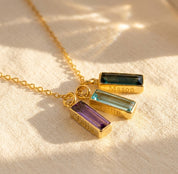 Custom birthstone name bar necklace with engraved names and colorful gemstone charms on a gold chain.