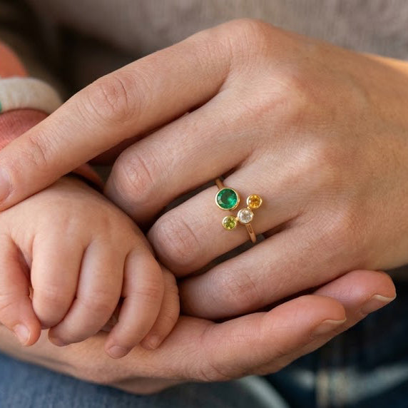 Woman wearing a personalized adjustable family birthstone ring with one Mom stone and three kids gemstones.

