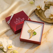 Custom initial and birthstone angel wing necklace in gold, memorial jewelry with personalized letter charm, angel wing pendant and green birthstone, sympathy gift for loss, remembrance jewelry in Danique gift box