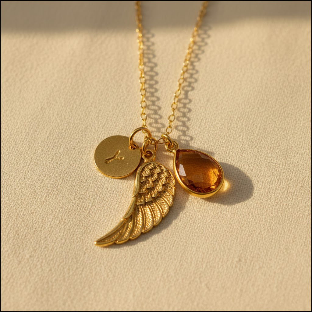 Personalized angel wing necklace featuring a natural birthstone teardrop, engraved initial disk, and gold vermeil wing charm, a meaningful memorial jewelry piece and sympathy gift for women.