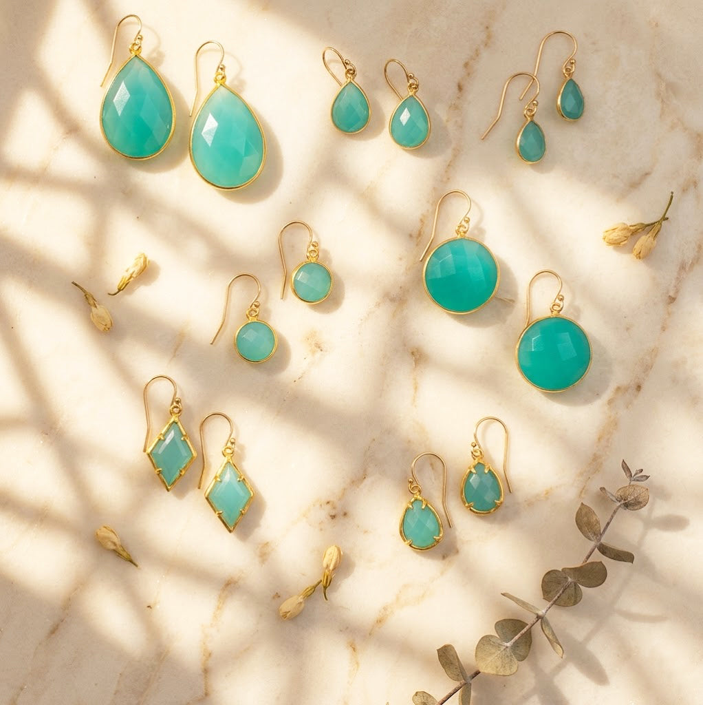 Aqua chalcedony earrings flat lay in warm light, gold March birthstone drop earrings in multiple shapes and sizes