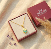 Close-up of aqua chalcedony necklace on model, engraved name charm and teardrop birthstone pendant in gold in Danique Jewelry Branded Box