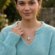 Model wearing aqua chalcedony teardrop pendant necklace with engraved charm, elegant aquamarine-inspired jewelry