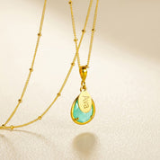 Personalized aqua chalcedony name necklace in gold with engraved oval charm and teardrop March birthstone pendant