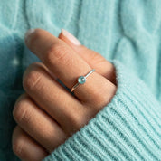 march birthstone aqua chalcedony ring worn on a woman’s hand, showing the slim minimalist band and bezel-set gemstone that stacks beautifully with other dainty rings, crafted in sterling silver or gold vermeil, perfect for everyday wear, personalized birthstone stacks, or meaningful gifts for mom, daughter, sister or best friend, soft natural light emphasizes the calming blue-green hues of the chalcedony stone and the delicate handcrafted design