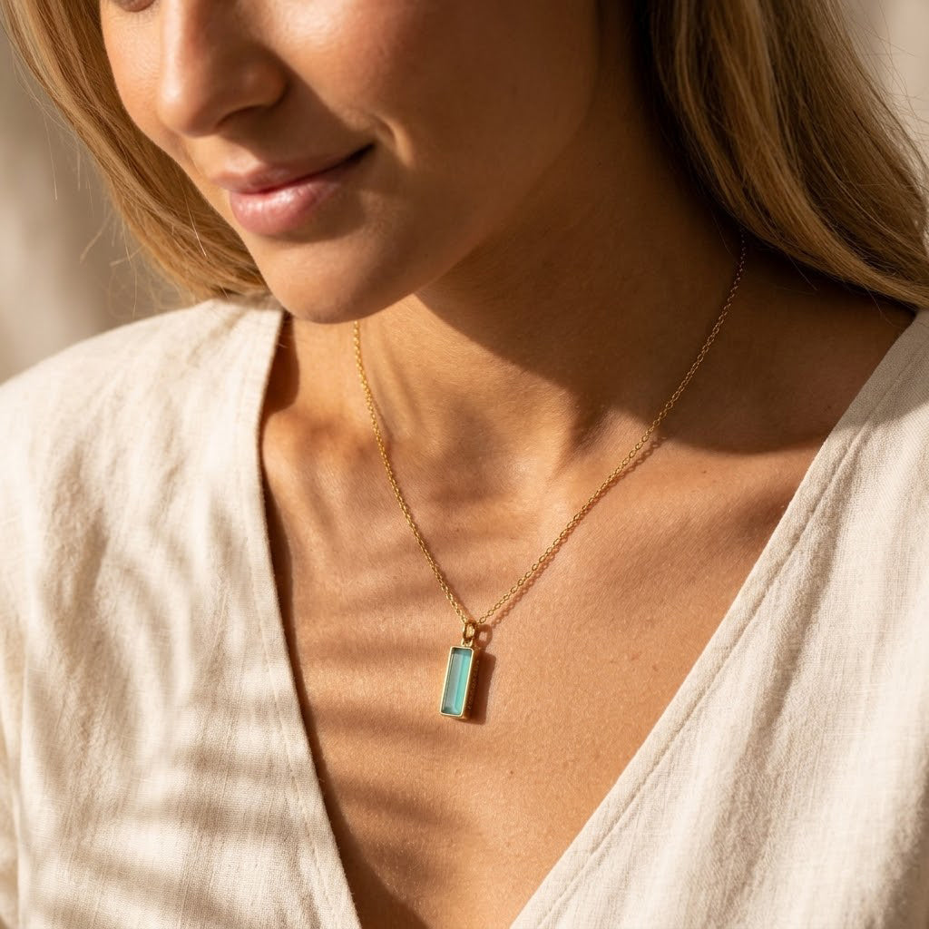Model wearing a March birthstone bar necklace with aqua chalcedony pendant and personalized side engraving.