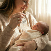 Lifestyle image of a mother holding a personalized baby photo keychain beside her newborn, capturing an emotional moment. This engraved baby picture keychain is created from a real baby photograph and crafted as a heartfelt keepsake gift for new moms. Ideal for celebrating birth, motherhood, or preserving a baby’s earliest memories.