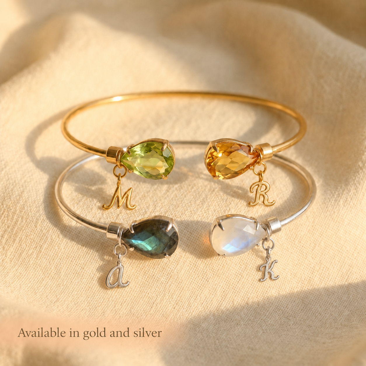 Two birthstone bangle bracelet with teardrop gemstones and initial charms, available in gold and sterling silver for a personalized gift.