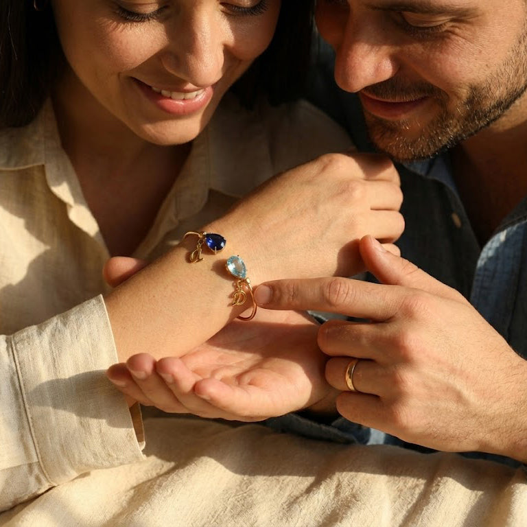 Couple holding hands with personalized birthstone initial bracelet, a romantic anniversary or him and her jewelry gift.