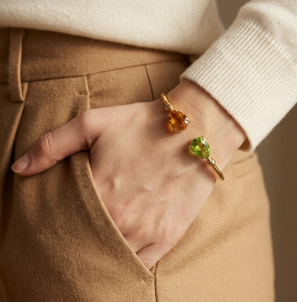 Custom two birthstone bangle bracelet worn on wrist, featuring two pear shaped gemstones chosen to represent loved ones or birth months.