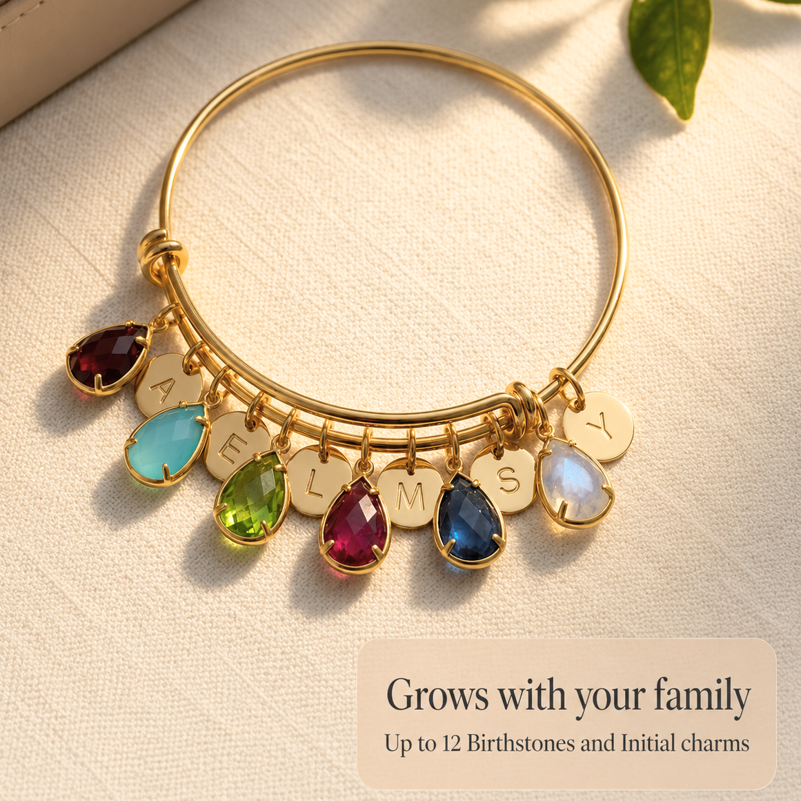 Gold custom birthstone bangle bracelet with initial charms and colorful teardrop birthstones, designed to grow with your family.