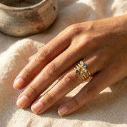 Custom birthstone stacking rings worn on hand with colorful gemstones and leaf initial charms, a meaningful personalized ring gift.
