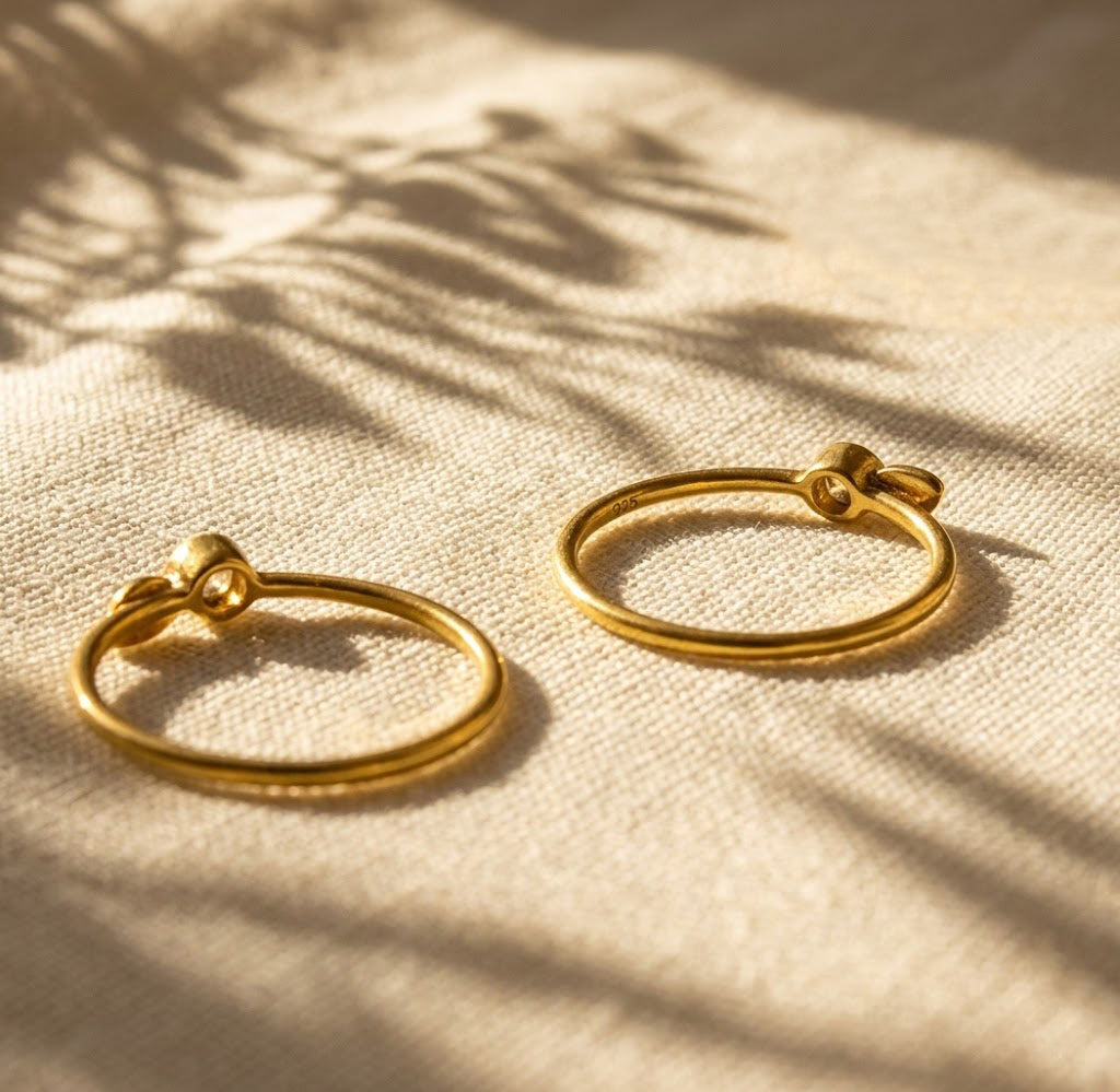 Pair of stackable birthstone initial rings in gold and sterling silver with small gemstone settings and leaf charms.