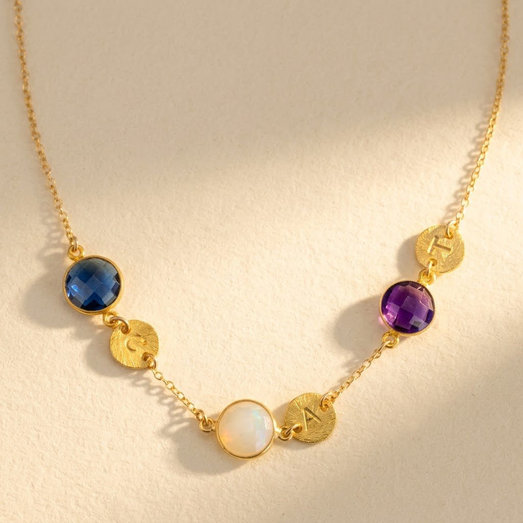 Mom necklace with custom birthstones and initial charms in gold on beige background