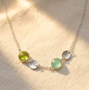 Custom birthstone necklace with initial charms hanging in natural light