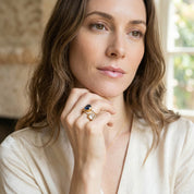Woman wearing a green onyx statement ring with a softly lit neutral outfit.
