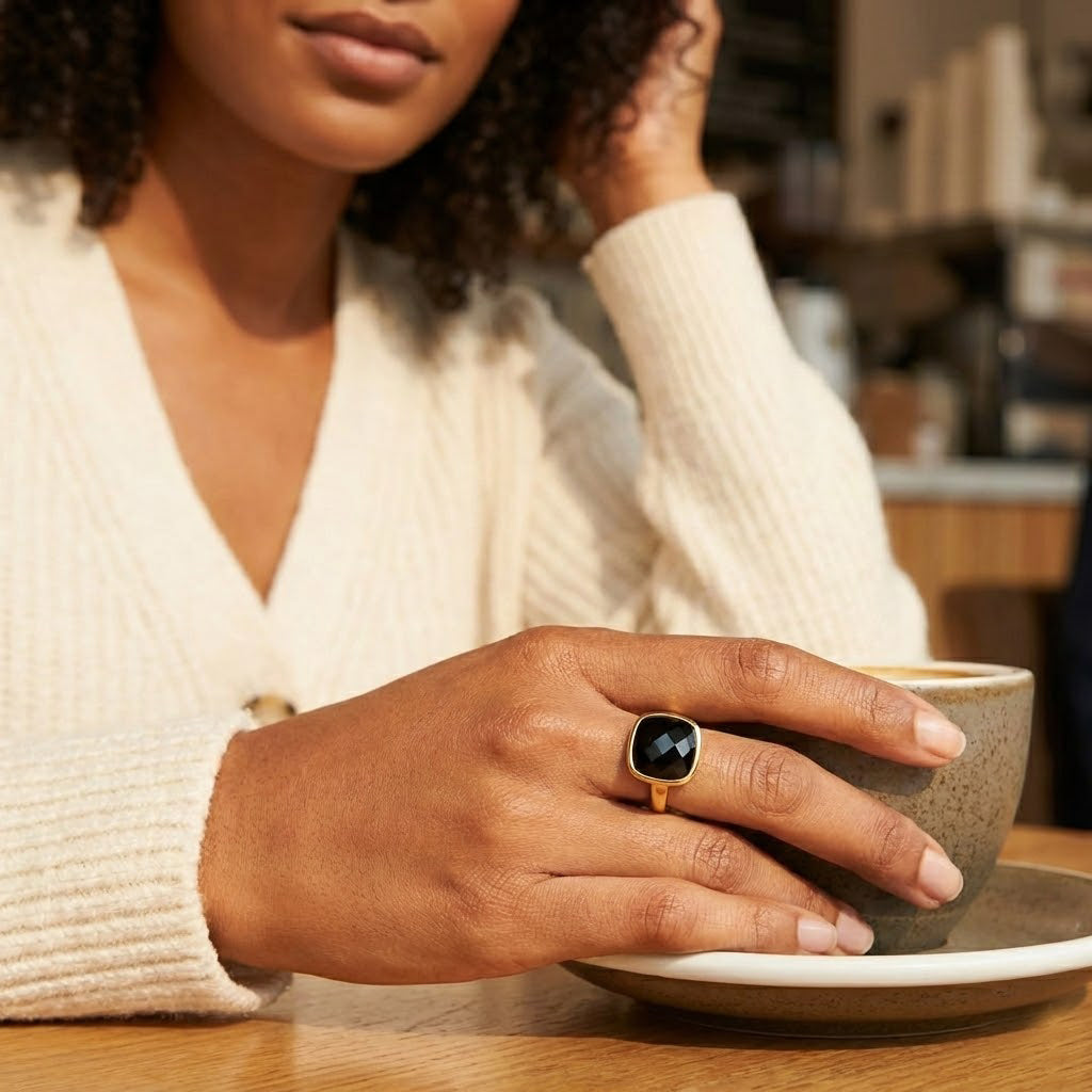 Close up of cushion cut black onyx ring in polished gold bezel setting, modern statement ring for women, sleek minimalist design with deep black gemstone contrast