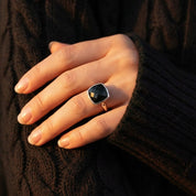 Black gemstone cushion ring worn on hand, elegant gold bezel black onyx ring for everyday wear, minimalist luxury statement jewelry for women, stacking friendly modern design