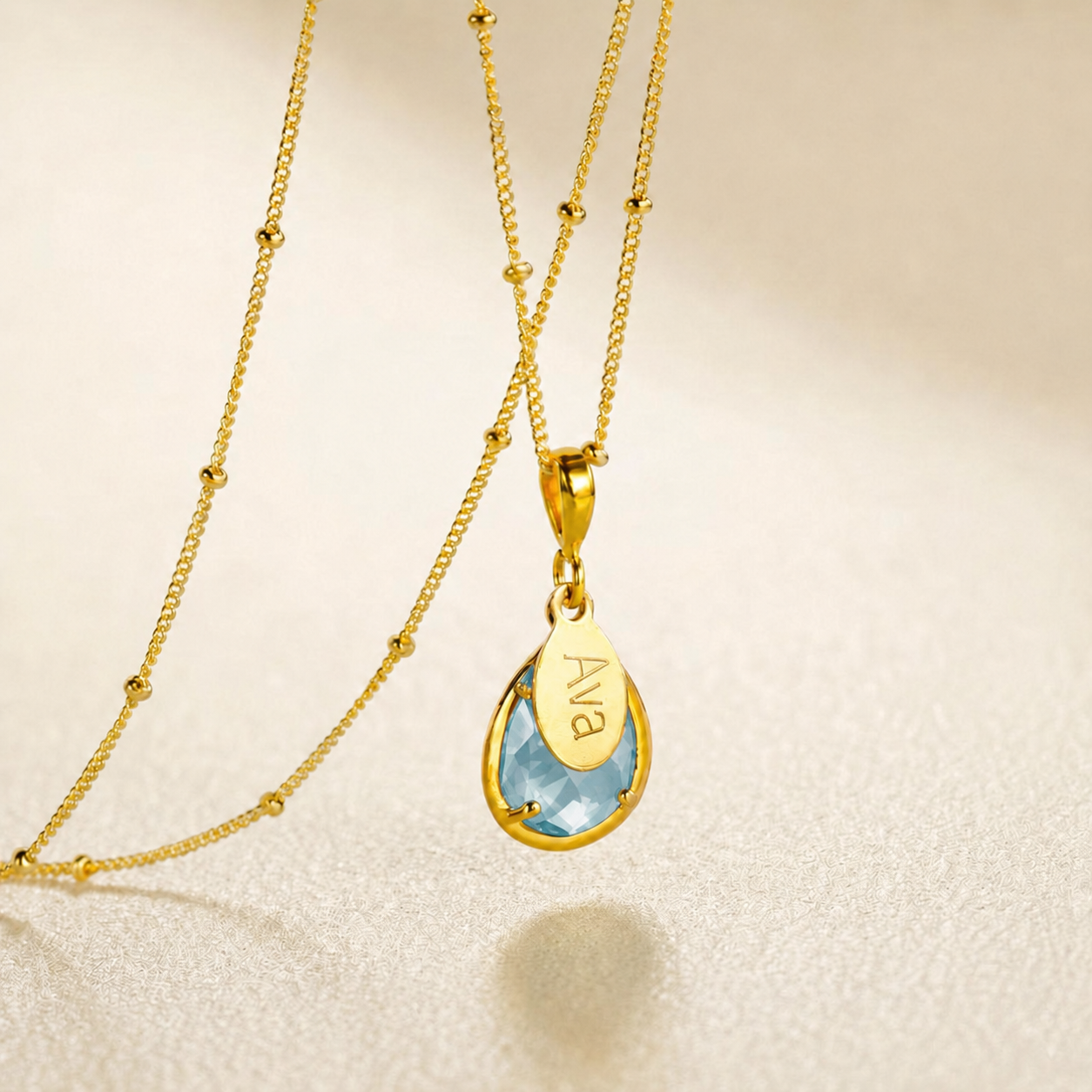 Gold blue topaz name necklace with sky blue teardrop pendant and engraved oval charm