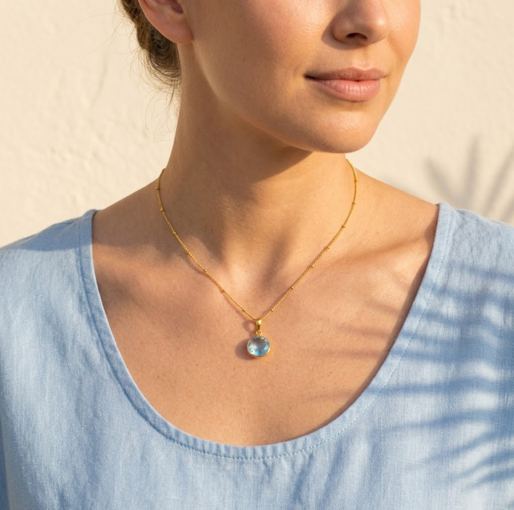 Blue topaz necklace on model, light blue gemstone pendant in gold, minimalist December birthstone jewelry