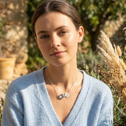 Blue topaz December birthstone necklace with custom letter charm on gold chain.
