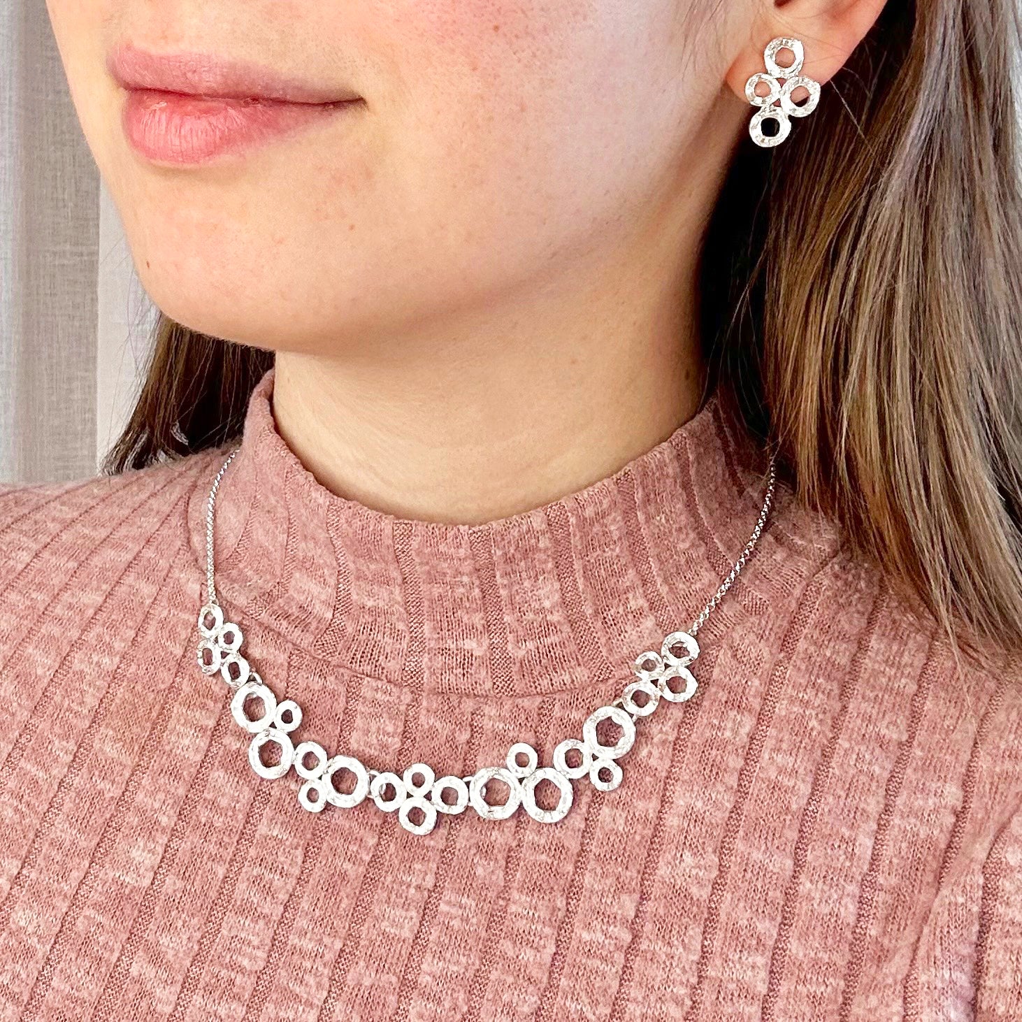 Model in pink turtle neck wearing the circles bubble necklace and earrings set. Bubble necklace, boho jewelry, boho necklace, boho earrings, gold, silver, pushback earrings, push back earring, stud earrings, statement necklace set, statement set, gift for her, gift for mom, mother's day jewelry, mother's day gift, nature inspired jewelry, nature inspired necklace