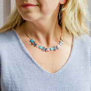 Pair of rose gold plated textured stacked squares necklace with rose gold, purple and pink square and rectangle pendants worn by a blonde model wearing a blue blouse