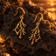 Gold coral branch dangle earrings with organic sculptural design on dark textured stone

