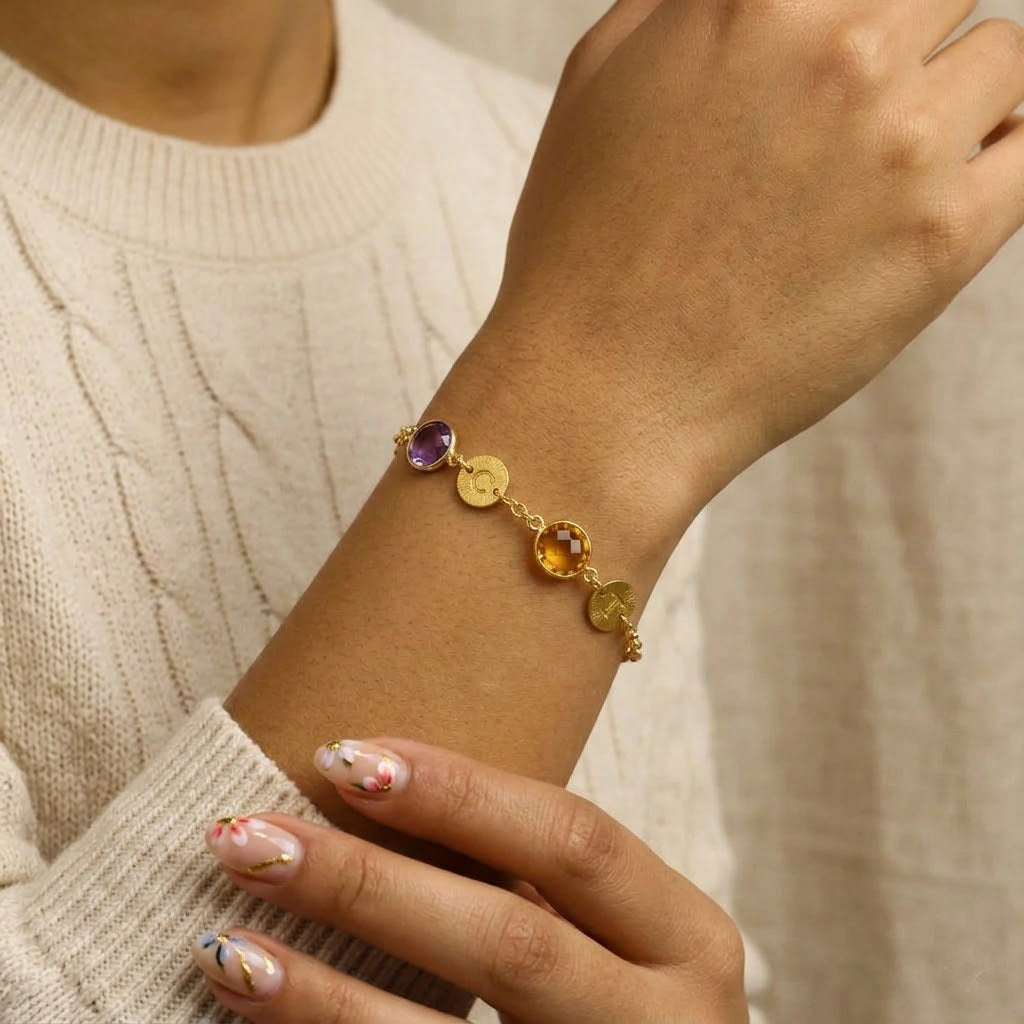 Personalized mom birthstone bracelet with engraved initial charms worn on wrist, dainty gold family bracelet representing children birthstones
