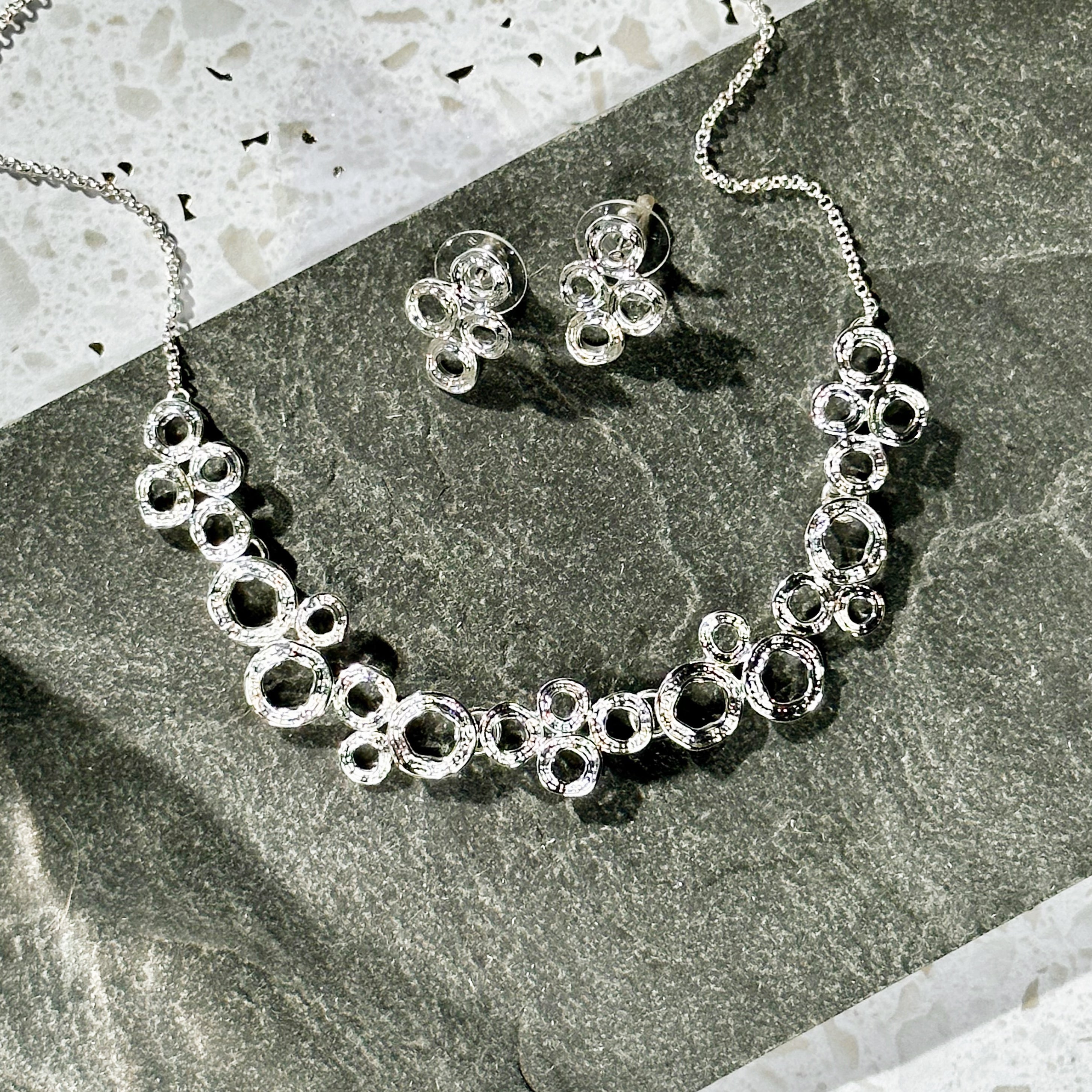 Zinc alloy with galvanic silver finish circles bubble necklace and earrings set on stone background. Bubble necklace, boho jewelry, boho necklace, boho earrings, gold, silver, pushback earrings, push back earring, stud earrings, statement necklace set, statement set, gift for her, gift for mom, mother's day jewelry, mother's day gift, nature inspired jewelry, nature inspired necklace