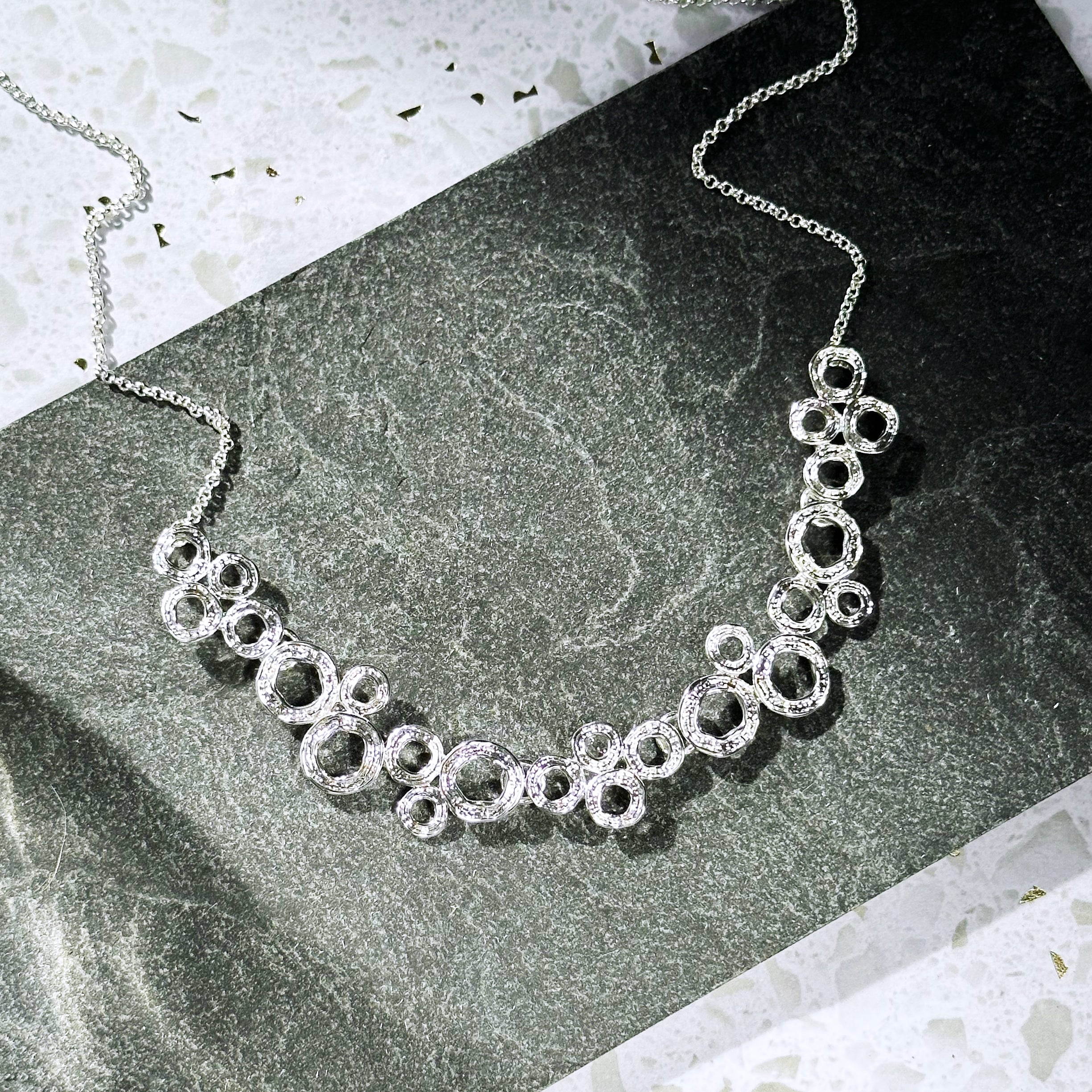 Zinc alloy with galvanic silver finish circles bubble necklace set on stone background. Bubble necklace, boho jewelry, boho necklace, boho earrings, gold, silver, pushback earrings, push back earring, stud earrings, statement necklace set, statement set, gift for her, gift for mom, mother's day jewelry, mother's day gift, nature inspired jewelry, nature inspired necklace