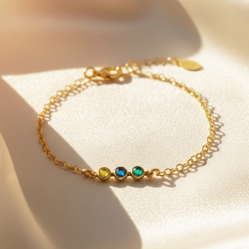 Dainty tiny cabochon birthstone bar bracelet in 14k gold filled with three bezel-set stones on a delicate chain, styled on soft champagne satin, minimalist stacking bracelet available in all birthstones, perfect personalized gift for mom, sister or friend.
