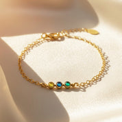 Dainty tiny cabochon birthstone bar bracelet in 14k gold filled with three bezel-set stones on a delicate chain, styled on soft champagne satin, minimalist stacking bracelet available in all birthstones, perfect personalized gift for mom, sister or friend.