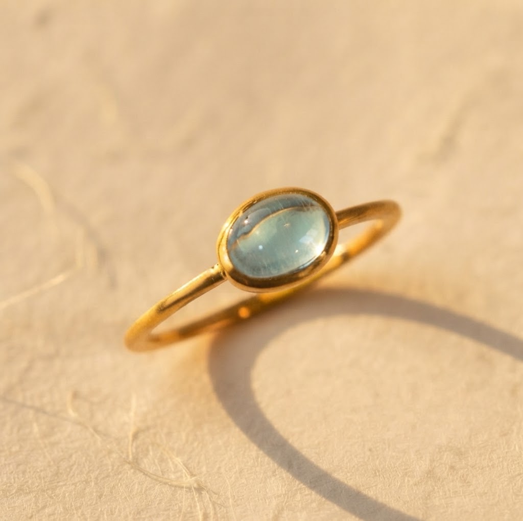 December blue topaz oval cabochon gemstone ring in a yellow gold bezel setting