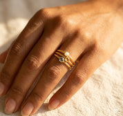 Custom tiny birthstone ring worn on hand, a delicate gold stacking ring personalized with a customer’s chosen cabochon gemstone.