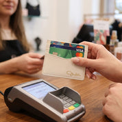 Person using a custom engraved PU leather card holder at a payment terminal, showing slim wallet design for credit cards.