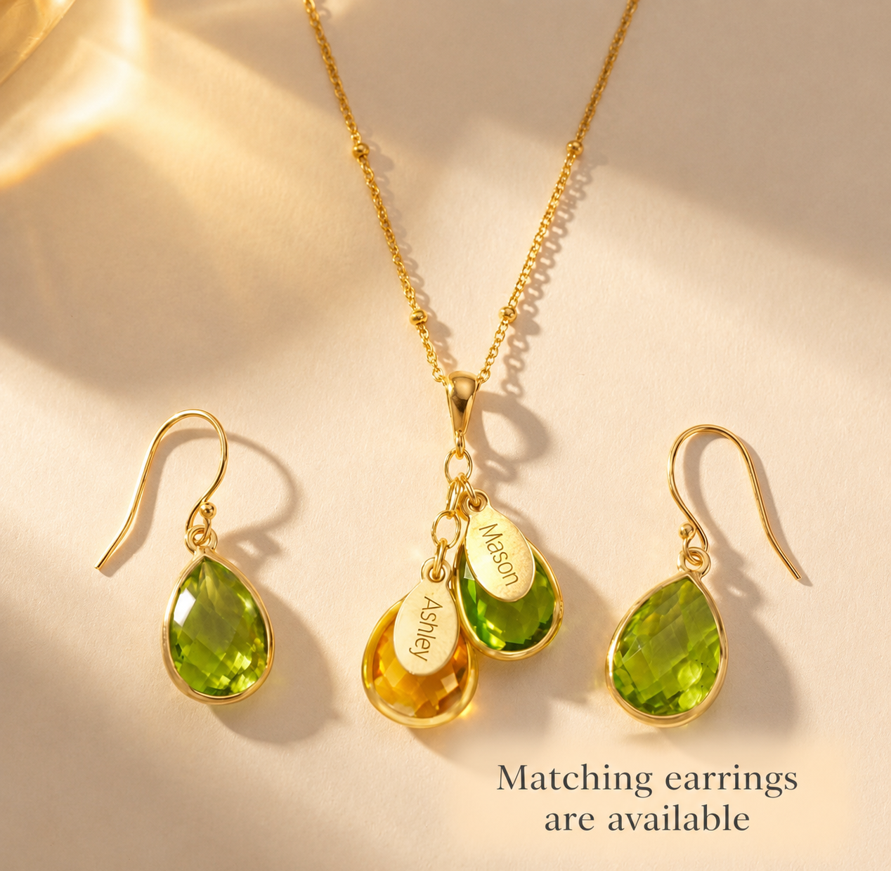 Matching birthstone necklace and earrings set with green gemstones and engraved oval name charms.