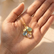 Custom birthstone necklace held in hand, showing cascading teardrop gemstones and initial charms for personalized mother’s jewelry.
