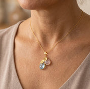 Model wearing custom family birthstone necklace, a delicate personalized mom necklace with cascading gemstone charms and initials.