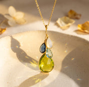Natural birthstone necklace with cascading teardrop gemstones on warm beige background, a meaningful personalized gift for mom or grandma.