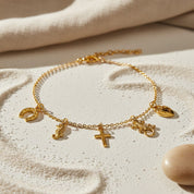 Personalized charm anklet displayed on textured sand background, custom gold filled anklet with dangling charms inspired by beach and summer jewelry, dainty handmade ankle bracelet for women featuring symbolic charms, adjustable charm anklet designed for warm weather styling, minimalist gold anklet perfect for vacations, seaside wear, layering with other anklets, and meaningful personalized jewelry gifts