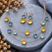Sea Glass Glow floating circles necklace and matching drop earrings displayed on gray stone

