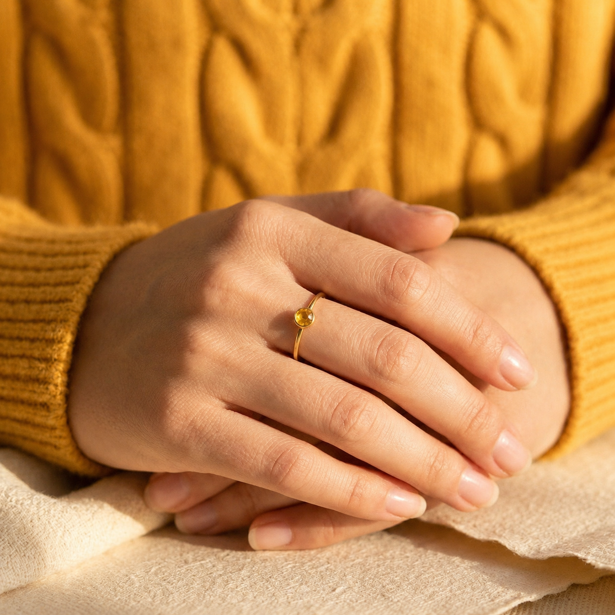 Woman wearing a delicate gold citrine ring with mustard knit sweater
