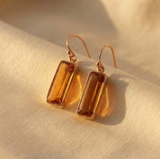 Citrine Quartz baguette earrings casting warm shadows on cream fabric