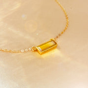 dainty citrine bar necklace featuring a baguette-cut yellow citrine gemstone set in an 18k gold filled vertical bar pendant, engraved name option along the side, delicate cable chain resting on soft champagne satin background, minimalist November birthstone necklace designed for everyday wear or layering with other gold necklaces, personalized gemstone jewelry perfect for birthday, anniversary, bridesmaid or holiday gifting for her