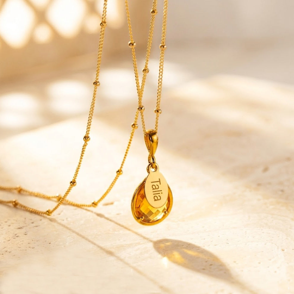 Radiant citrine November birthstone necklace featuring a prong-set teardrop gemstone paired with a custom engraved name tag in elegant script, shown on a delicate gold-filled chain. Personalized citrine pendant makes a meaningful November birthday gift for mom, grandma, daughter or best friend. Warm golden tones highlight the birthstone’s symbolism of joy and abundance. Available in sterling silver or 14k gold-filled with custom engraving.